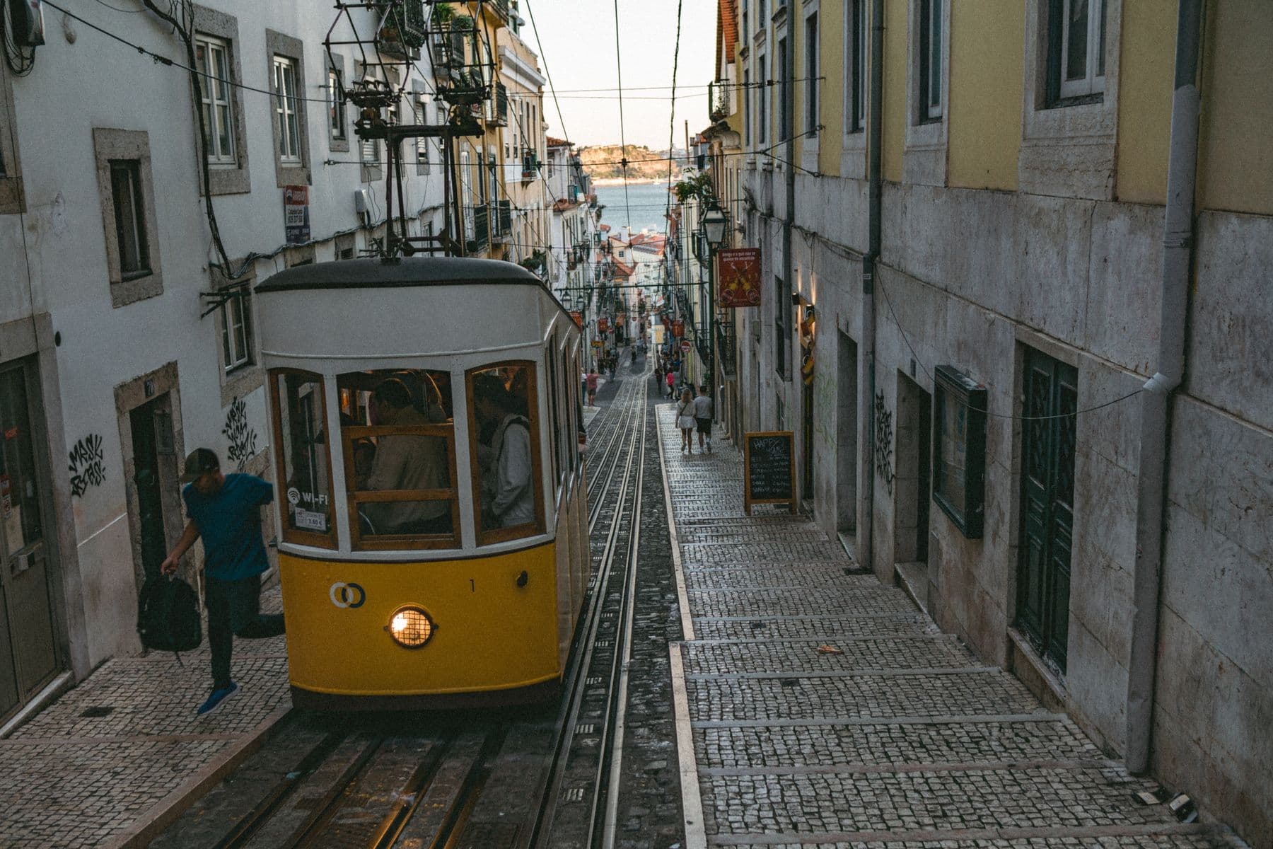 A yellow tram on a cobbled Lisbon street